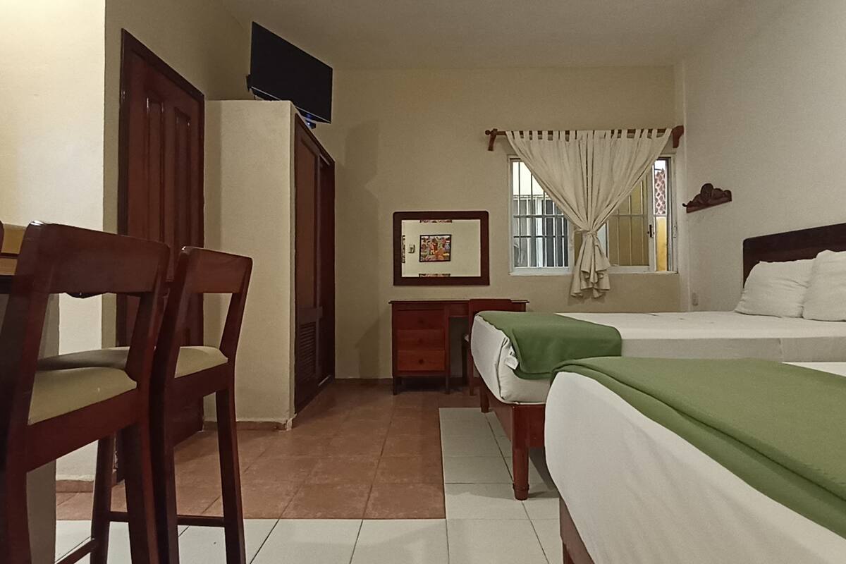 Un dormitorio con dos camas, un escritorio, sillas, un armario y un cuadro en la pared.