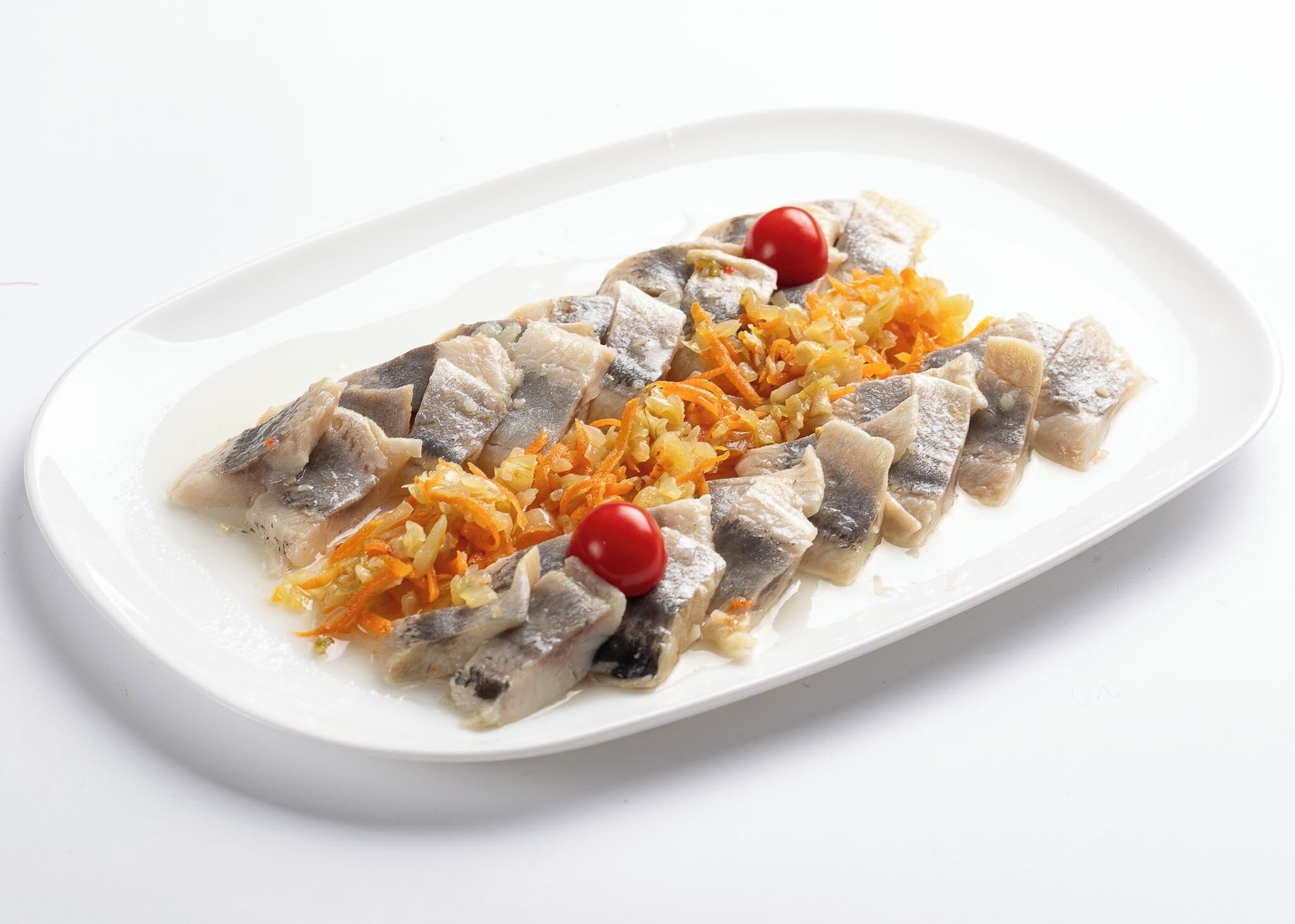 A white plate with sliced fish and shredded carrots, garnished with cherry tomatoes.