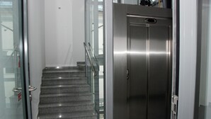A modern elevator with a metallic finish, a glass door, and a stainless steel interior. - Algiro Hotel (Kaunas)