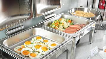 Un buffet proposant une variété de plats, notamment des œufs, des légumes et des saucisses.