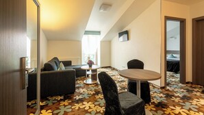 A modern hotel room with a sofa, chairs, a small table, and a patterned carpet. - Algiro Hotel (Kaunas)