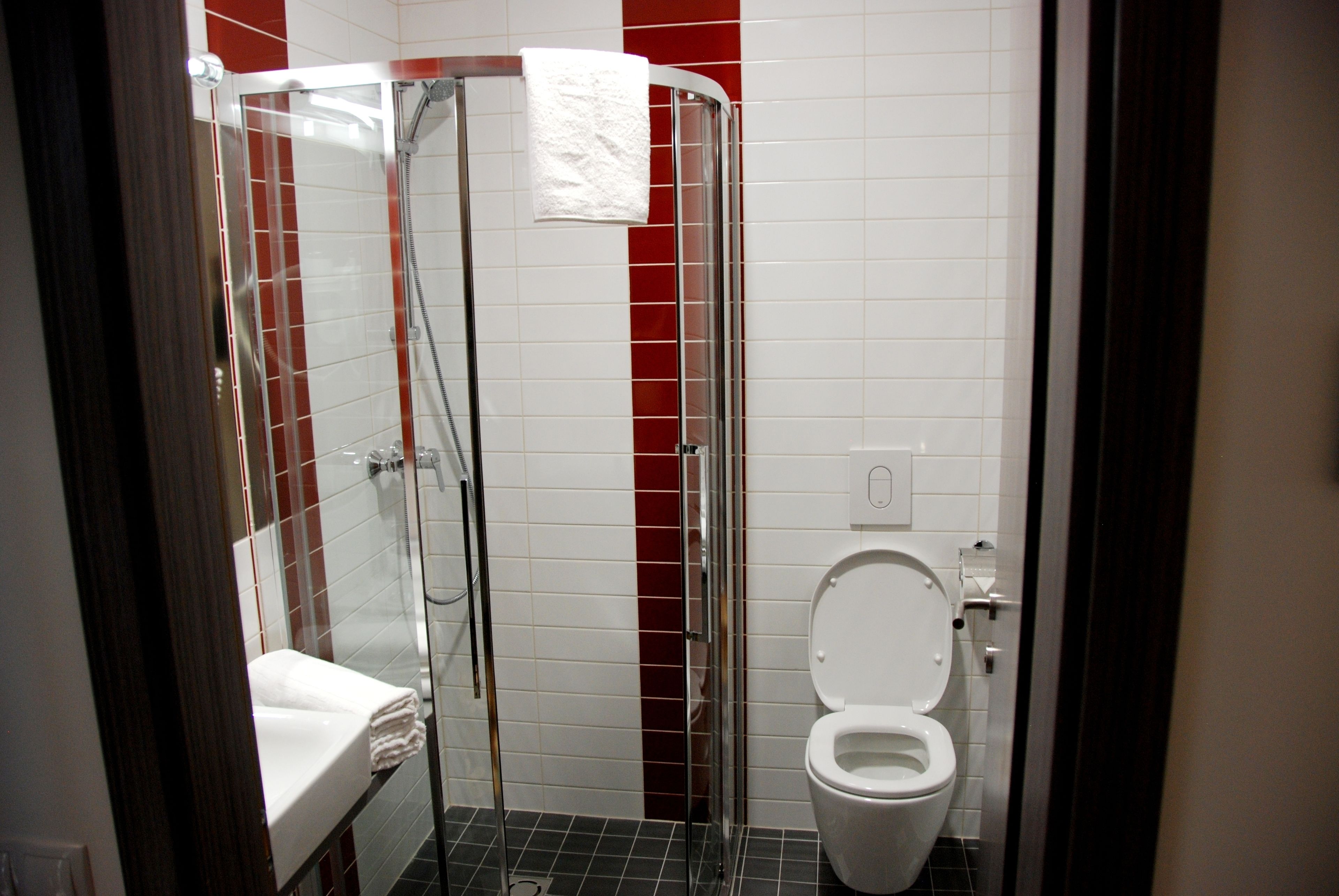 A bathroom with a glass-enclosed shower, a white toilet, and a sink with a towel.