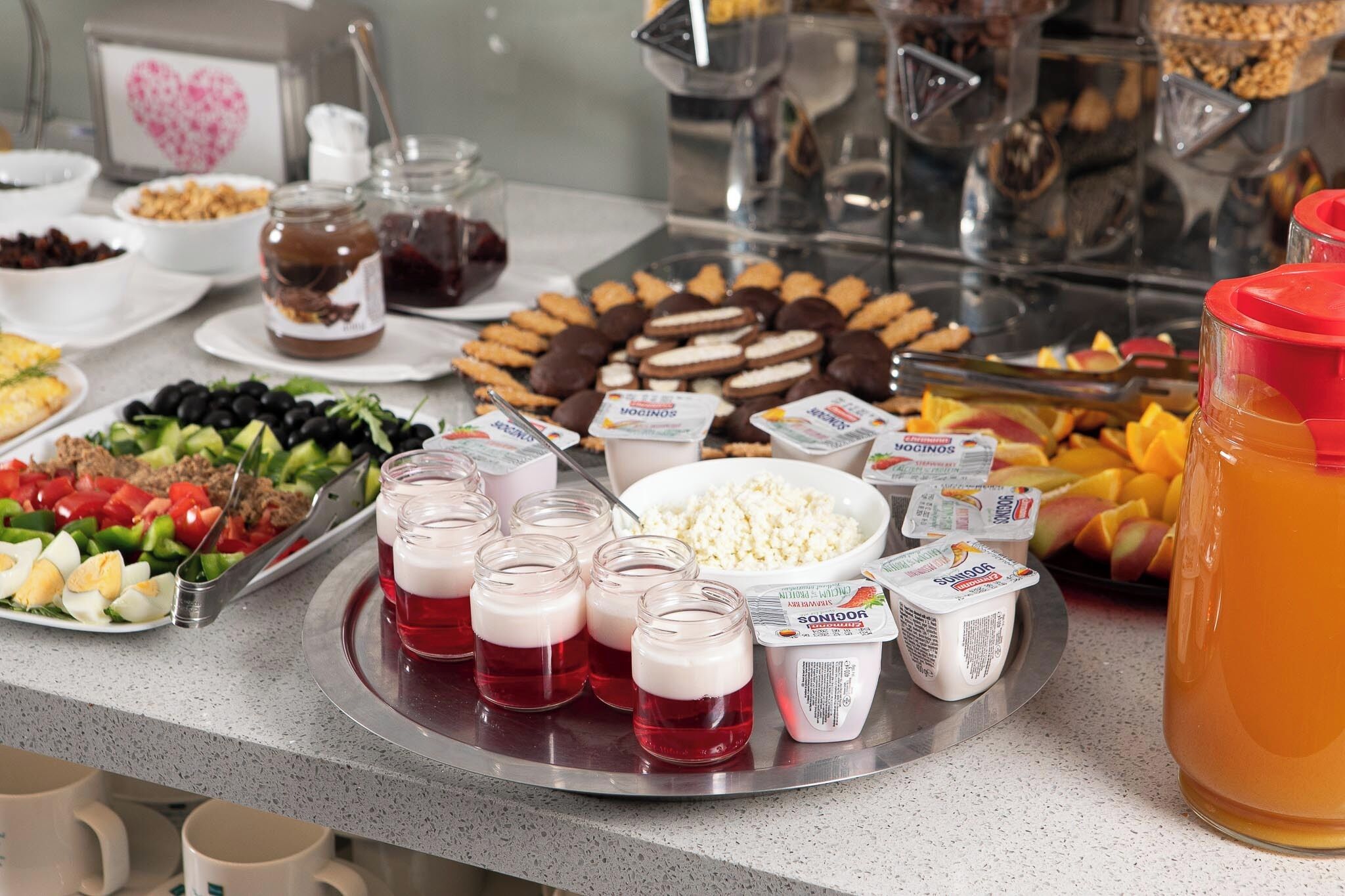 En buffet med forskellige retter, herunder salater, frugt og drikkevarer.