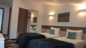 Una habitación de hotel con dos camas, un armario de madera, un espejo y un cuadro en la pared.