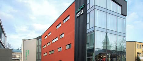 Un hotel moderno con fachada roja y grandes ventanales.