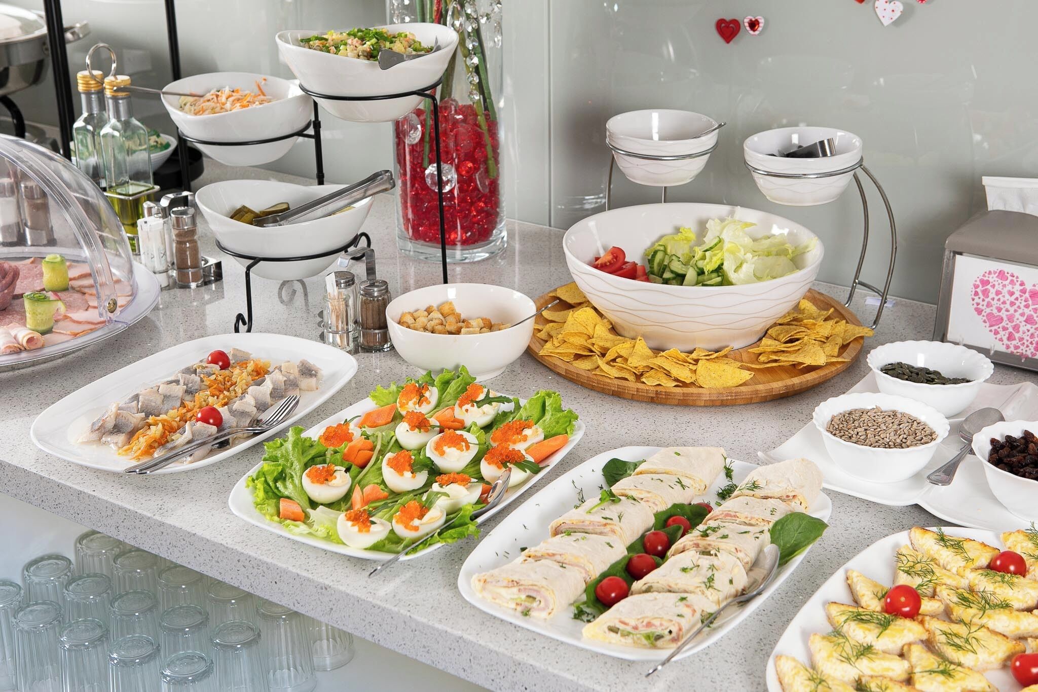 Mesa de buffet com diversos pratos, incluindo saladas, carnes e petiscos.