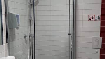 A modern bathroom with a glass-enclosed shower, white tiled walls, a white sink with a marble countertop, and a white toilet.