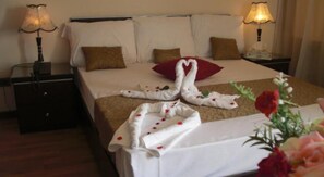 A hotel room with a neatly made bed, two nightstands with lamps, and a floral arrangement on the bedside table. - Cairo plaza Guest House (Sheikh Zayed City)