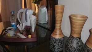 A hotel room with a table set with a coffee cup, a glass of tea, a bottle of water, a tea bag, a kettle, and two patterned vases. - Cairo plaza Guest House (Sheikh Zayed City)