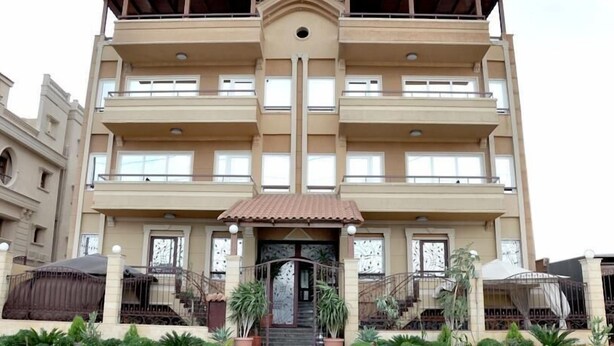 A multi-story building with a central entrance, balconies, and potted plants. - Cairo plaza Guest House (Sheikh Zayed City)