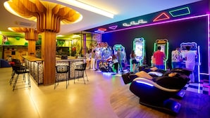 Un espace de détente moderne doté d’un bar, de jeux d’arcade et de fauteuils de massage.