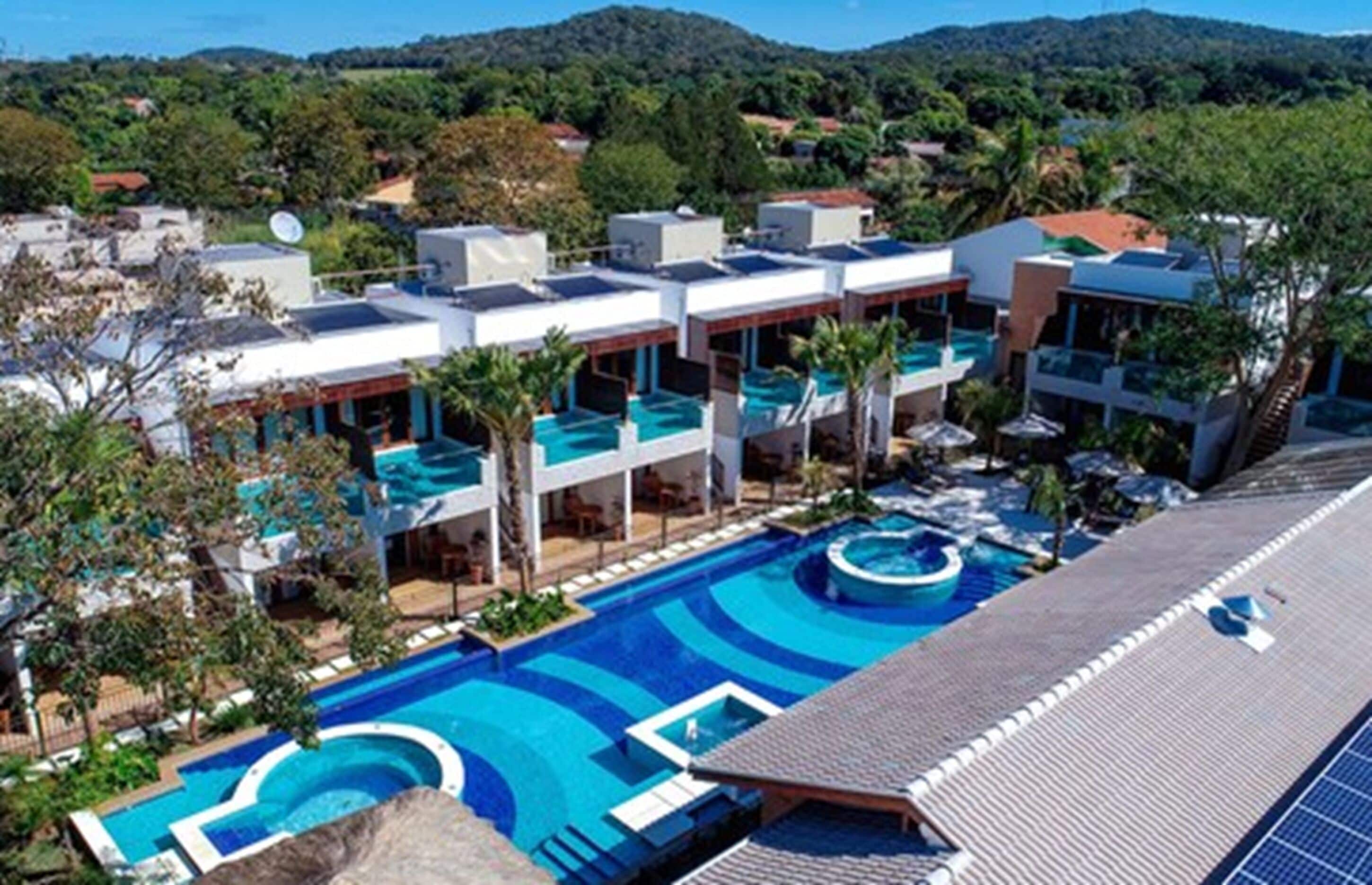 A resort with multiple swimming pools, modern architecture, and a view of the surrounding landscape.