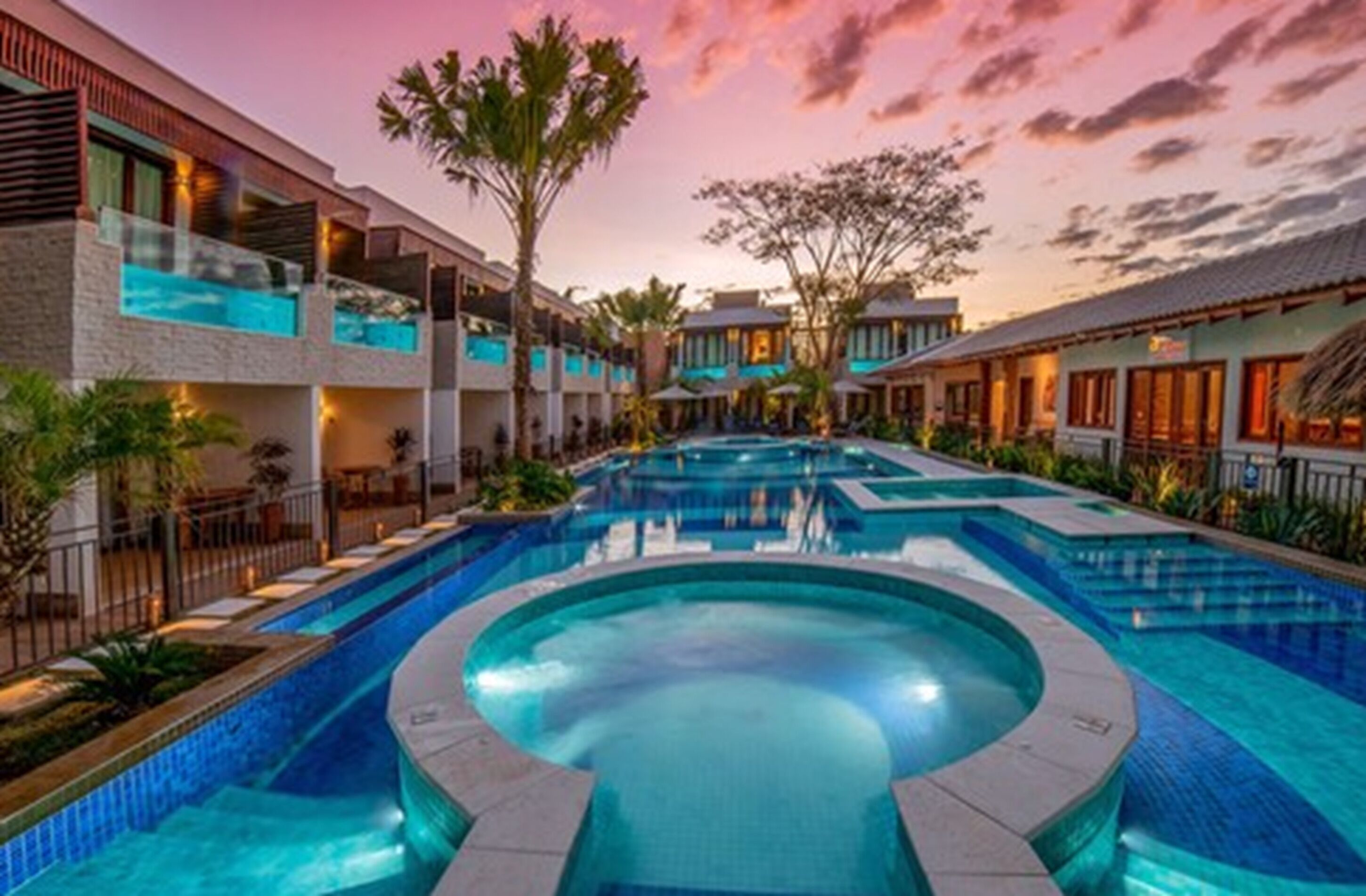 Een resort met een centraal gelegen zwembad, diverse gastenkamers en een tropische tuin.
