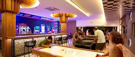 A bar area with arcade games, a foosball table, and a pool table.