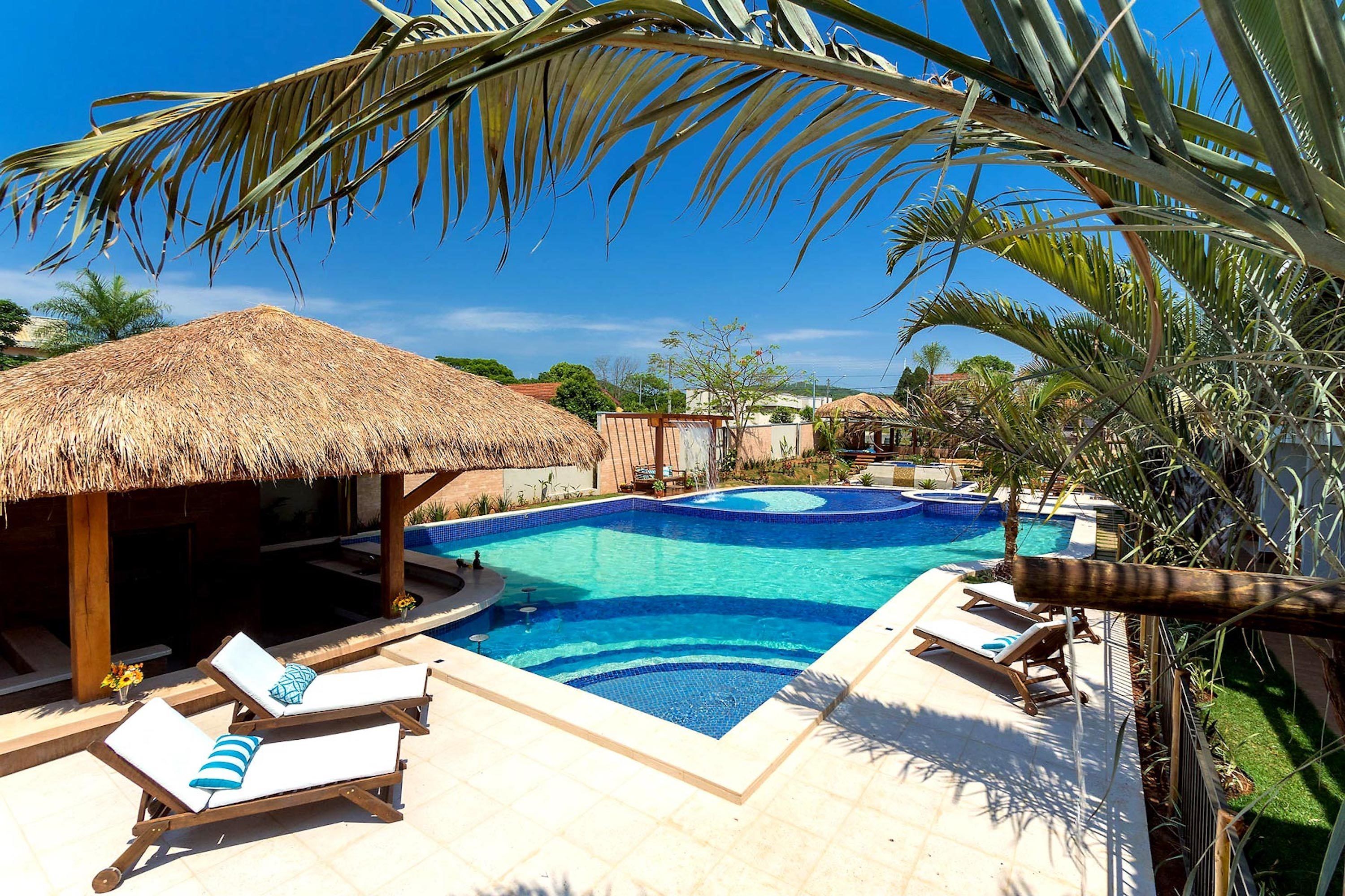 A swimming pool with lounge chairs and a thatched-roof structure.