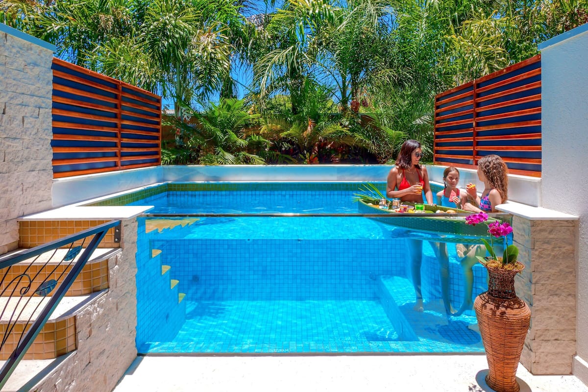 Una piscina con paredes de azulejos, una escalera de piedra y un jarrón decorativo con flores.