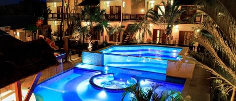 Een binnenzwembad, 3 buitenzwembaden en parasols bij het zwembad