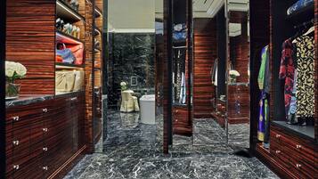 A luxurious walk-in closet with marble flooring and wooden cabinetry, featuring a variety of handbags and clothing.