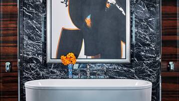 A bathroom with a marble sink, a framed abstract artwork, and a vase with flowers.