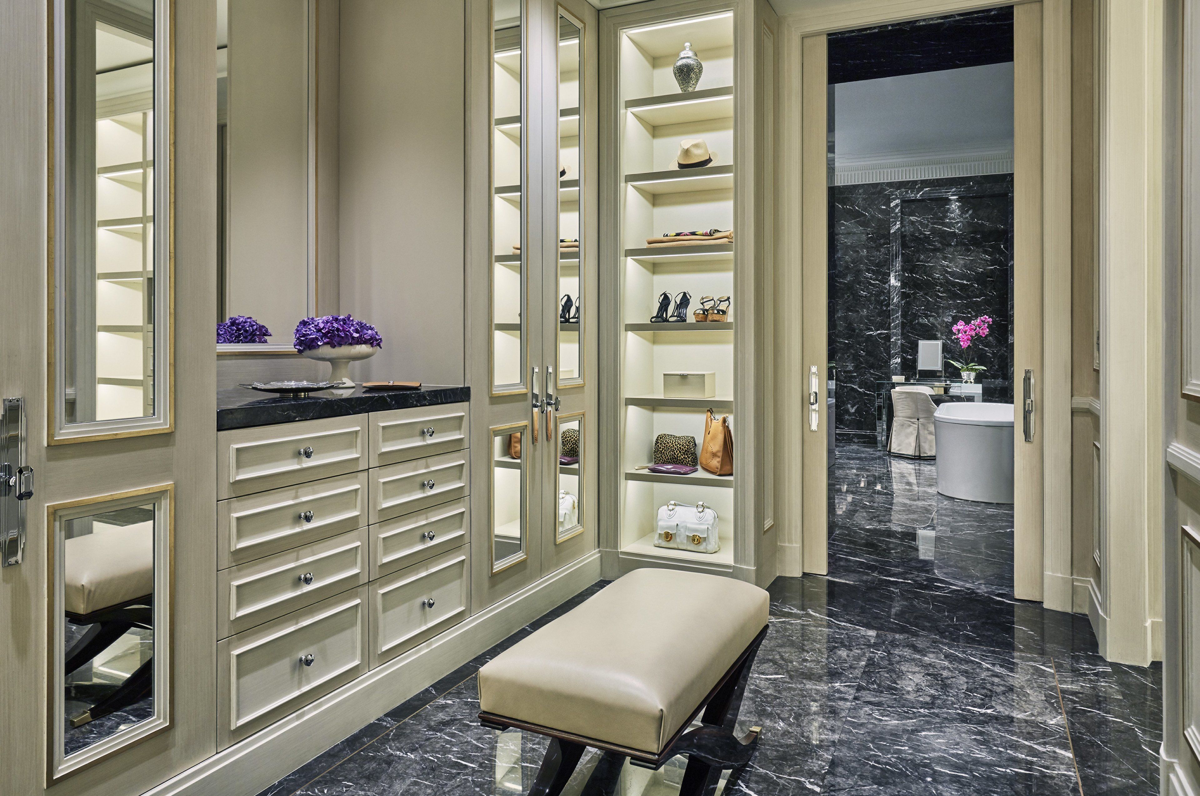 A spacious bathroom with a marble floor, a large mirror, and a vanity with a sink and countertop.