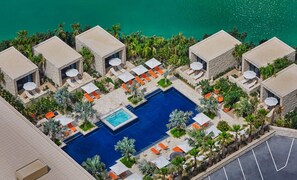 A resort with a central pool, multiple lounge areas with umbrellas, and a view of the sea. - Four Seasons Hotel Bahrain Bay (Manama)