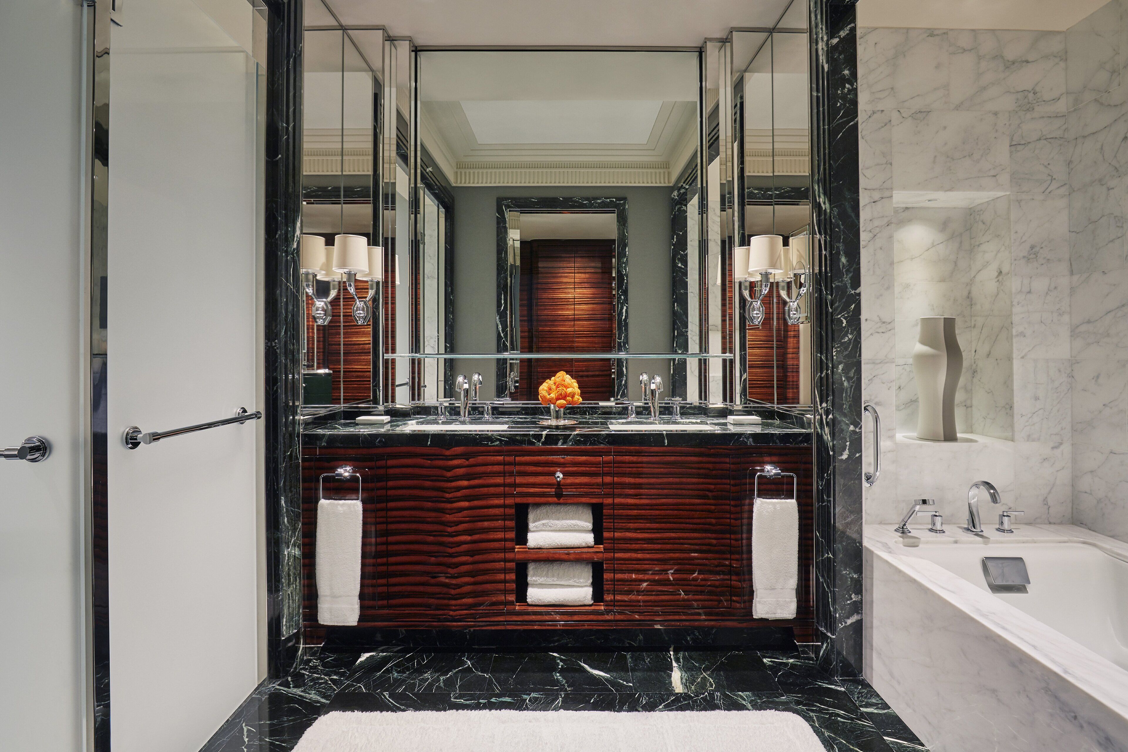 Un baño lujoso con tocador de mármol, doble lavabo y un espejo grande.