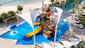A water park with slides and a pool area, surrounded by beach and lounge chairs. - Four Seasons Hotel Bahrain Bay (Manama)