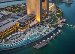 A waterfront hotel with a pool, lounge areas, and a large building with vertical columns. - Four Seasons Hotel Bahrain Bay (Manama)