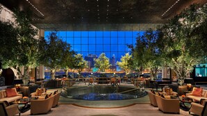 A spacious lobby with a large central water feature, multiple seating areas, and a view of the cityscape through a large window. - Four Seasons Hotel Bahrain Bay (Manama)