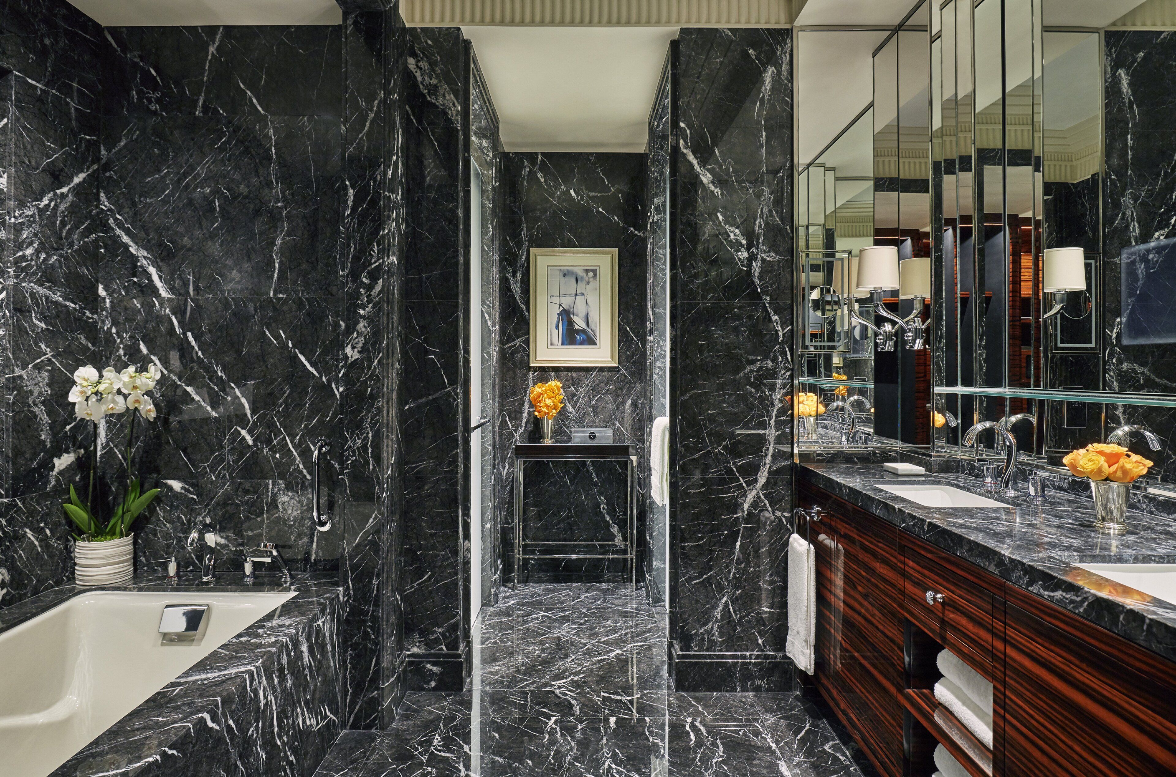 A modern bathroom with a marble floor, a bathtub, a vanity with a mirror, and a framed picture on the wall.