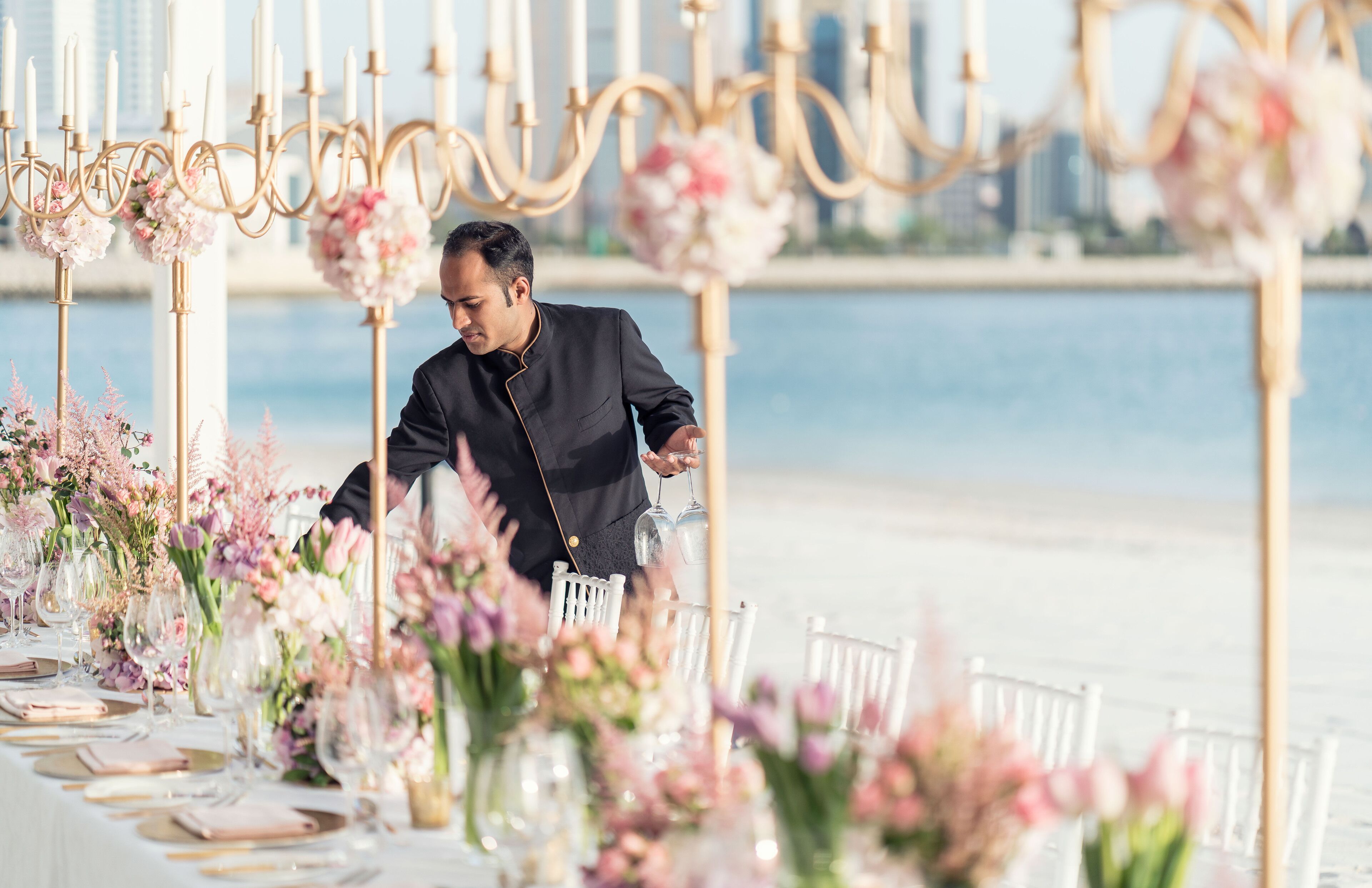 A table set for a formal event with floral centerpieces and a cityscape view in the background.