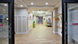 A modern hotel corridor with a wooden floor, glass doors, and a reception desk. - Hampton by Hilton Bar Harbor (Bar Harbor)