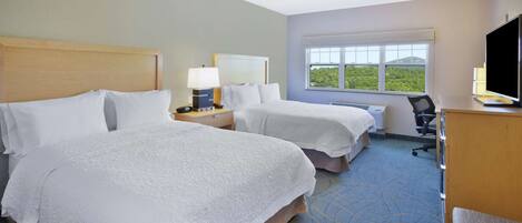 A hotel room with two beds, a desk, a chair, a TV, and a window with a view.
