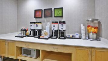 A self-service beverage station with multiple coffee makers, a microwave, and a fruit punch dispenser.