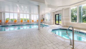 An indoor swimming pool with clear water, tiled floor, and orange chairs along the poolside. - Hampton by Hilton Bar Harbor (Bar Harbor)