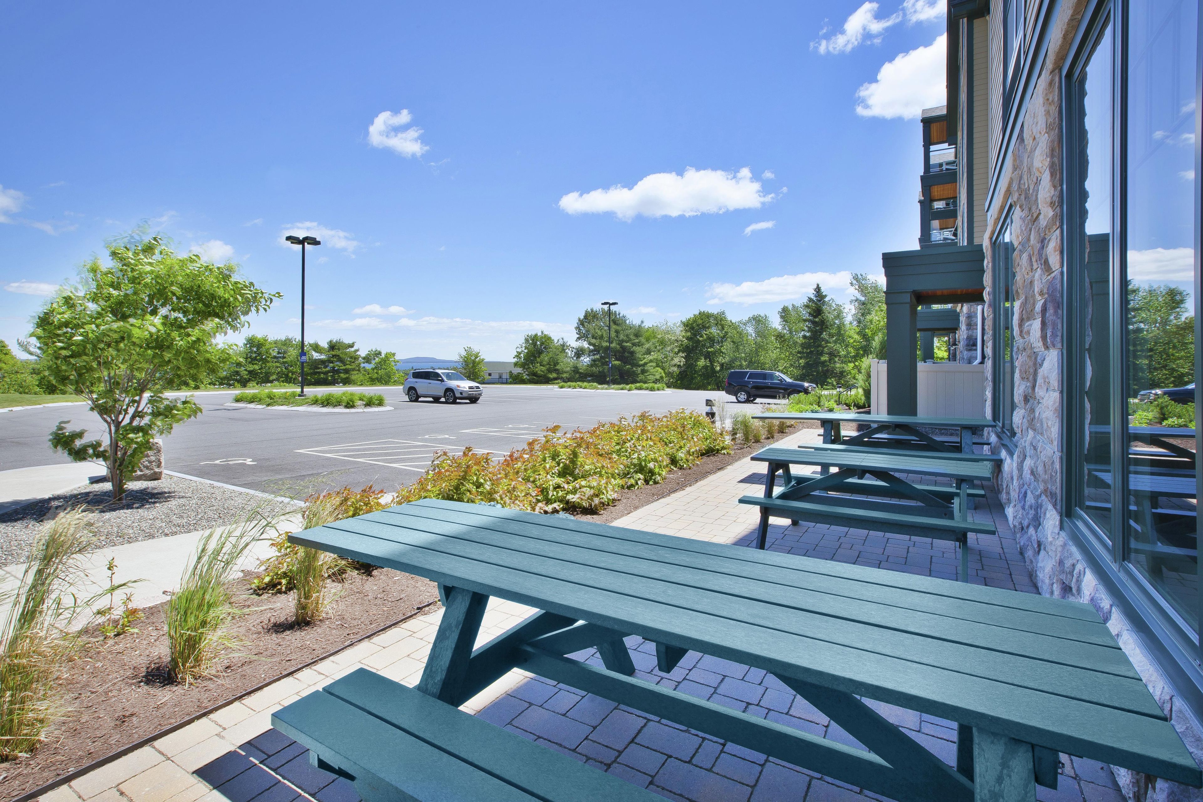 A parking lot with picnic tables and a building with stone facade.