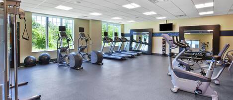 Un gimnasio con cintas de correr, elípticas y pesas sueltas.
