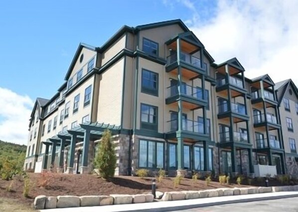 A multi-story hotel with balconies, large windows, and a landscaped front yard. - Hampton by Hilton Bar Harbor (Bar Harbor)