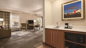 A hotel room with a kitchenette, a dining area with a table and chairs, a sofa, and a large window with curtains. - Hampton Inn Brigham City (Brigham City)