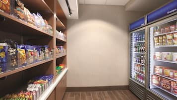 A grocery store with shelves stocked with snacks and a refrigerated section with beverages.