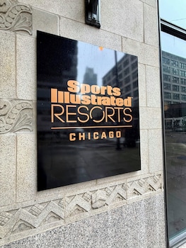 A modern bathroom with two sinks, a large mirror, and a window providing natural light. at Sports Illustrated Resorts Chicago