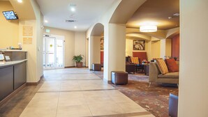 A hotel lobby with a reception desk, a 100% smoke-free sign, an exit sign, and a seating area with a couch and chairs. - Candlewood Suites Fort Collins by IHG (Fort Collins)