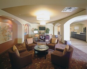 A hotel lobby with a seating area, a flat-screen TV, a reception desk, and a patterned carpet. - Candlewood Suites Fort Collins by IHG (Fort Collins)