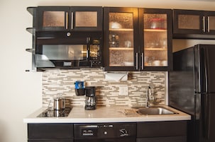 Una cocina moderna con gabinetes negros, un refrigerador de acero inoxidable, una cafetera y un microondas.