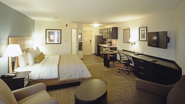 A hotel room with a bed, desk, office chair, and a TV. - Candlewood Suites Fort Collins by IHG (Fort Collins)
