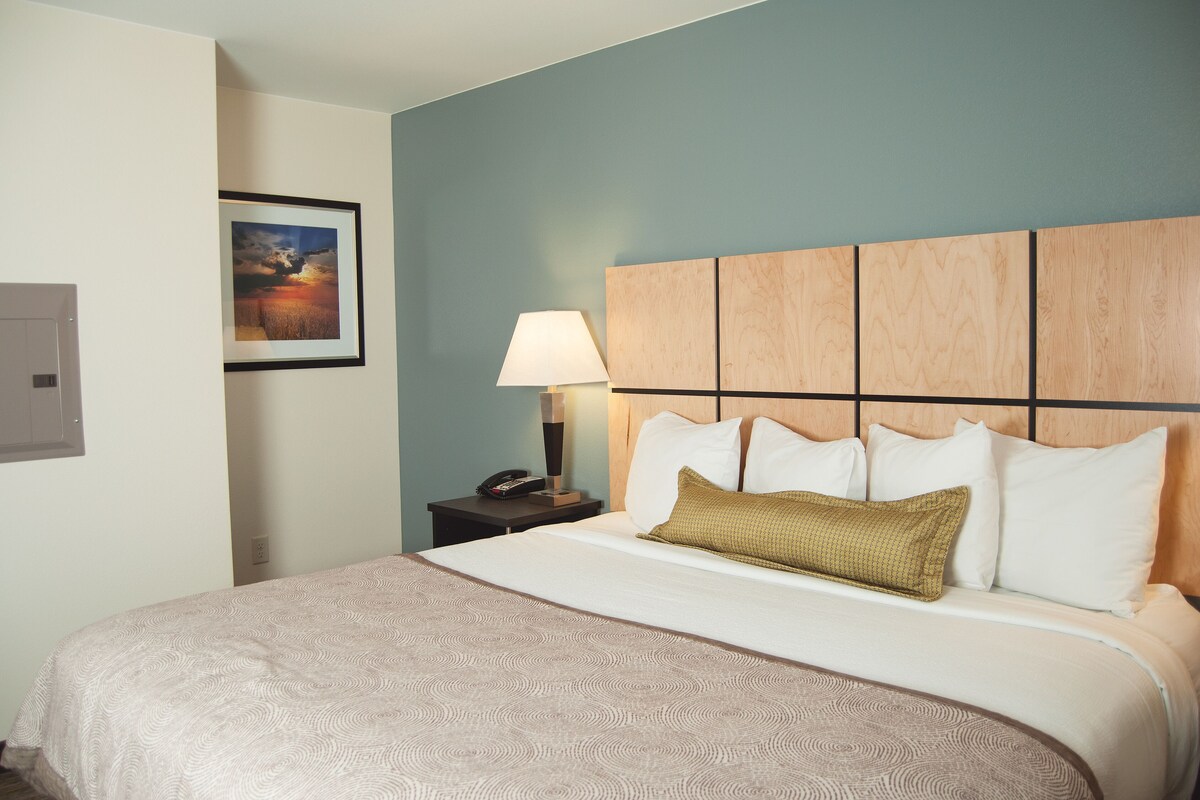 A neatly made bed with a patterned bedspread, a wooden headboard, and a bedside lamp.