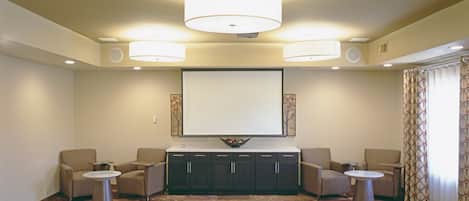 Una habitación amplia con un televisor de pantalla plana grande montado en la pared, una zona de estar cómoda con sofás y sillones, y una alfombra estampada.