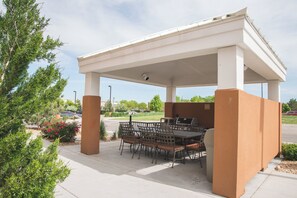 An outdoor patio with a covered grill area, seating, and a view of the surrounding landscape. - Candlewood Suites Fort Collins by IHG (Fort Collins)