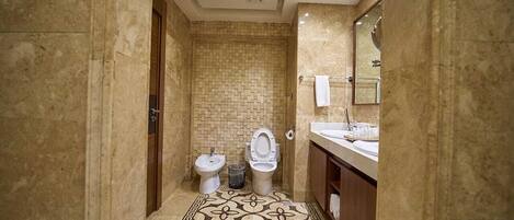 A bathroom with a tiled floor, a bidet, a toilet, a sink, and a mirror.