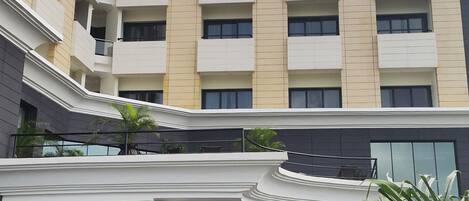 A multi-story hotel with a central courtyard, featuring a fountain and potted plants.